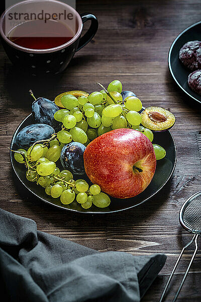 Teller mit Früchten - Apfel  weiße Trauben und Pflaumen