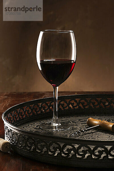 Ein Glas Rotwein mit Korkenzieher auf Tablett