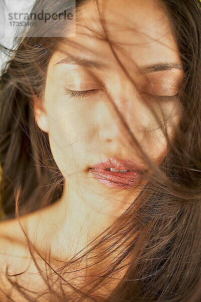 Studioaufnahme einer Frau mit braunen  zerzausten Haaren und geschlossenen Augen