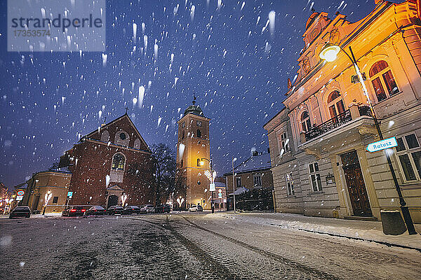 Polen  Karpatenvorland  Rzeszow  beleuchtete Straße mit Kirche im Winterschneefall in der Nacht