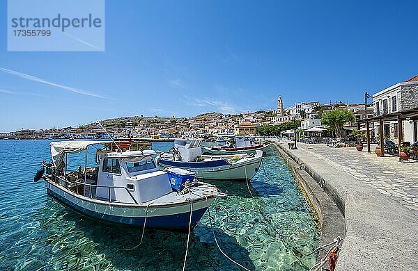 Fischerboote im Hafen von Chalki mit türkisblauem Wasser  Promenade mit bunten Häusern des Ortes Chalki  Chalki  Dodekanes  Griechenland  Europa