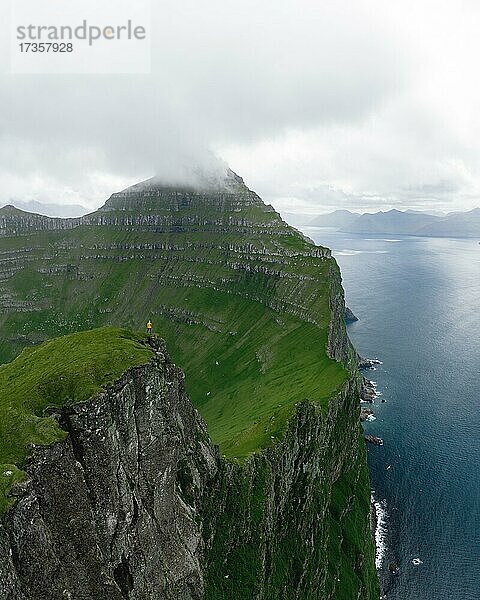Luftaufnahme  Person steht auf hoher Klippe  markante Berge im Hintergrund  Kalsoy  Faroer Inseln