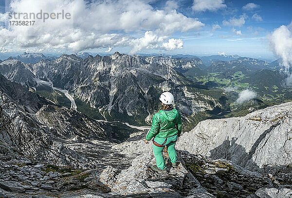 Wanderin mit Helm am Gipfel des Watzmann  Ausblick über Berge  Gebirgszug Hochkalterstock mit Blaueisspitze und Hochkalter  Wanderweg zum Watzmann  Watzmann-Überschreitung  Berchtesgaden  Bayern  Deutschland  Europa