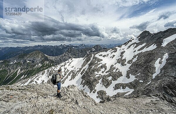 Wanderer beim Abstieg in felsigem Gelände  hinten Bergpanorama mit Altschneefeldern und felsigen Berggipfeln  Heilbronner Weg  Allgäuer Alpen  Allgäu  Bayern  Deutschland  Europa