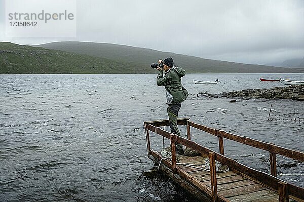 Wanderer fotografiert auf einem Holzsteg über dem Leitisvatn See  Vagar  Faroer Inseln