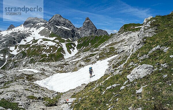 Wanderin in einem Schneefeld  Bergsteigerin auf Wanderweg  hinten Altschneefelder und felsige Gipfel der Mädelegabel und Trettachspitze  Bergpanorama  Heilbronner Weg  Allgäuer Alpen  Allgäu  Bayern  Deutschland  Europa