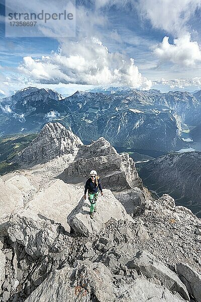 Wanderin mit Helm am Gipfel der Watzmann-Mittelspitze  Ausblick über Berge  Königssee und Obersee  Wanderweg zum Watzmann  Watzmann-Überschreitung  Berchtesgaden  Bayern  Deutschland  Europa