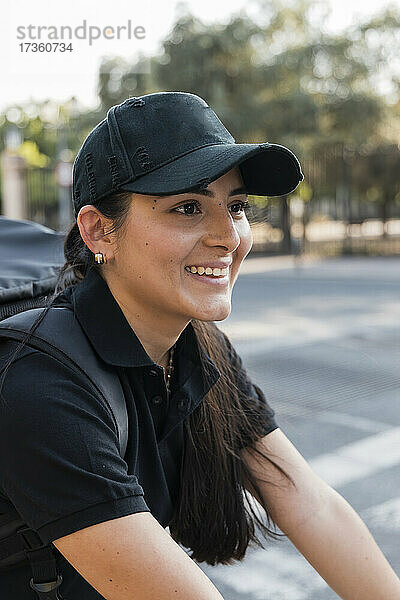 Lächelnder junger Angestellter eines wichtigen Dienstes mit schwarzer Kappe