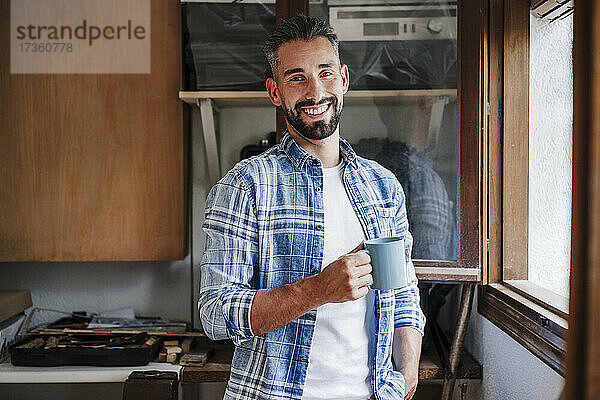 Männlicher Fachmann hält Kaffeetasse in der Werkstatt