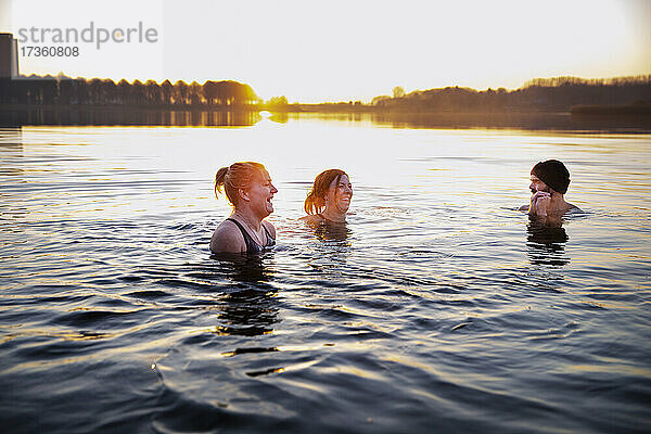 Fröhliche Frauen  die sich im Wasser vergnügen und einen männlichen Freund ansehen