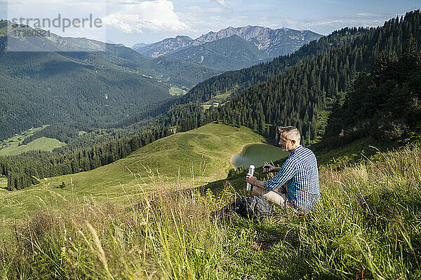 Männlicher Wanderer mit Blick auf den Berg an einem sonnigen Tag