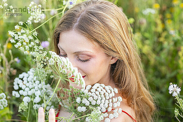Lächelnde Frau mit geschlossenen Augen  die an Blumen riecht