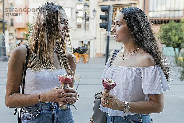 Junge Frauen halten Eistüten und schauen sich in der Stadt an