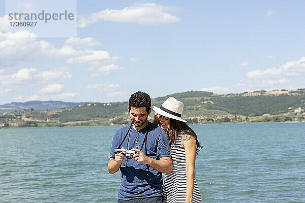 Paar überprüft Kamera  während es an einem sonnigen Tag am See steht