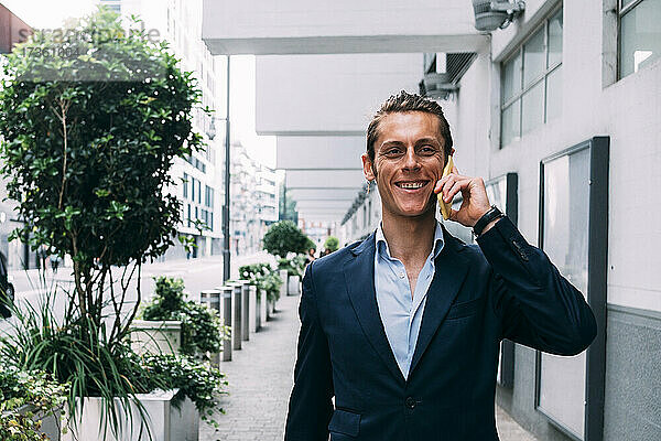 Lächelnder Geschäftsmann  der mit einem Mobiltelefon spricht
