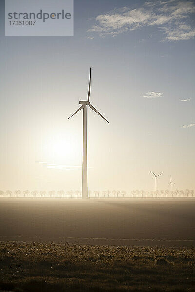 Windkraftanlage bei nebligem Sonnenaufgang