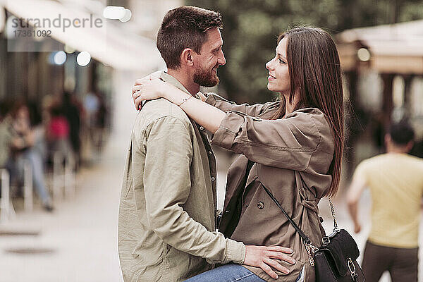 Lächelnde Frau  die den Arm um ihren Freund legt und ihn ansieht