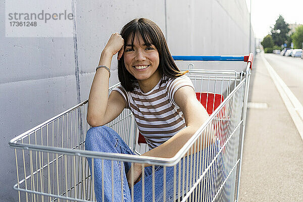Lächelnde Frau mit Pony im Einkaufswagen sitzend