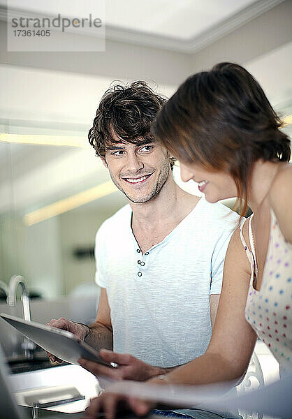 Lächelnder Mann teilt digitales Tablet mit Freundin zu Hause