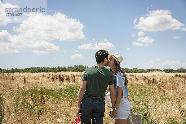 Paar küsst sich im Stehen an einem sonnigen Tag