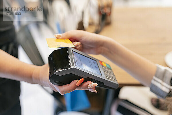 Frau zahlt mit Kreditkarte an Kellnerin im Food Court