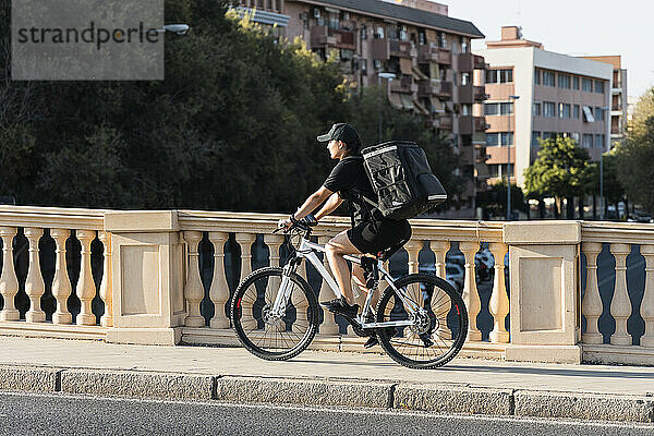 Junge Frontarbeiterin fährt mit dem Fahrrad auf dem Fußweg