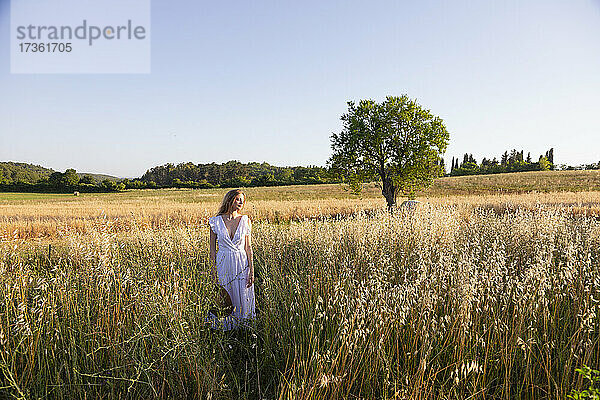 Junge Frau mit geschlossenen Augen und Hut in einem grasbewachsenen Feld