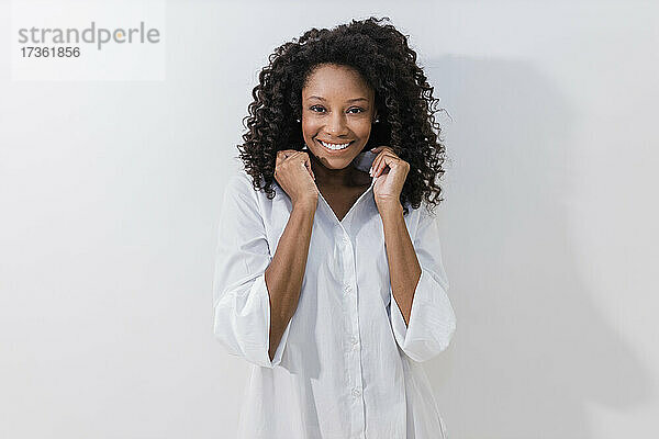 Junge Frau lächelt  während sie ein Halsband vor weißem Hintergrund hält