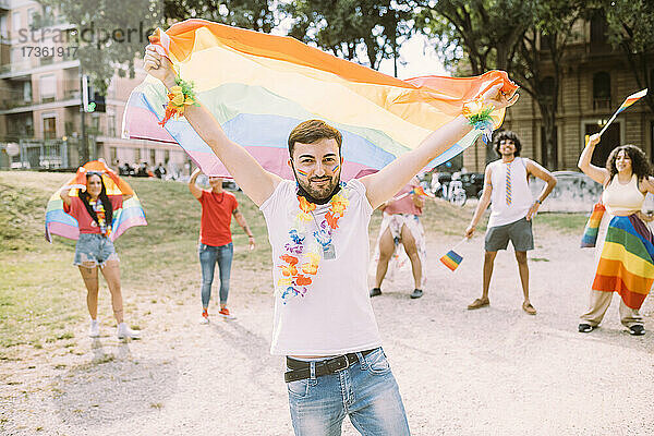 Junger Mann mit Flagge bei Pride-Event im Park