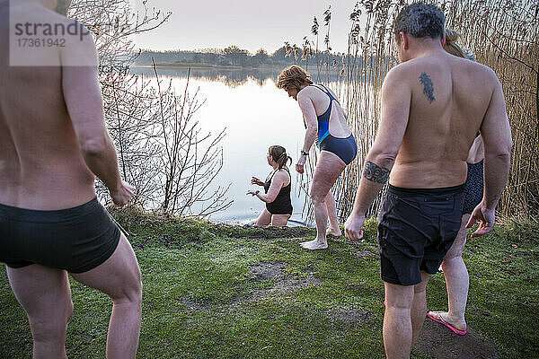 Männliche und weibliche Freunde schauen auf eine im Wasser gestikulierende Frau