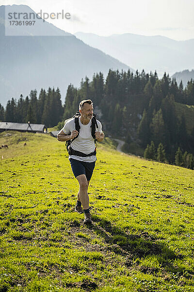 Männlicher Rucksacktourist beim Wandern in den Bergen an einem sonnigen Tag