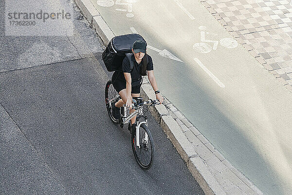 Junge Frau mit Rucksack auf dem Fahrrad auf der Straße