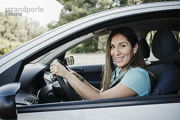 Lächelnde junge Frau am Steuer eines Autos