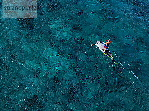 Luftaufnahme eines Mannes beim Paddeln im blauen Wasser des Nord Male Atolls