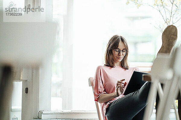 Berufstätige Frau bei der Arbeit mit digitalem Tablet in einem Cafe