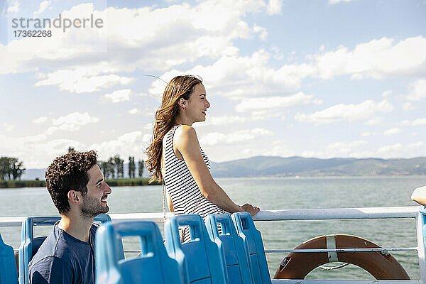 Frau schaut auf den Trasimenischen See  während sie neben einem Mann in einem Passagierboot steht