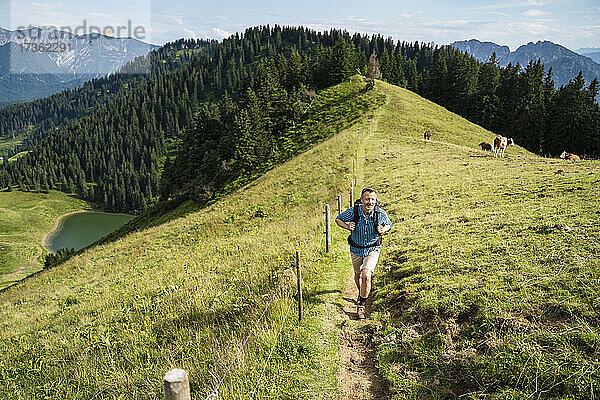 Männlicher Wanderer beim Wandern auf einem Bergpfad an einem sonnigen Tag