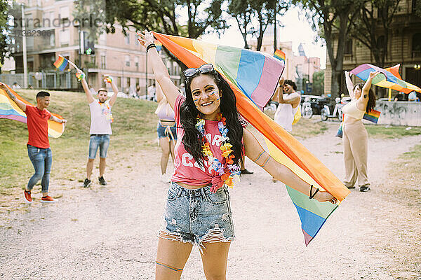 Lächelnde Frau mit Regenbogenfahne bei Pride-Event im Park