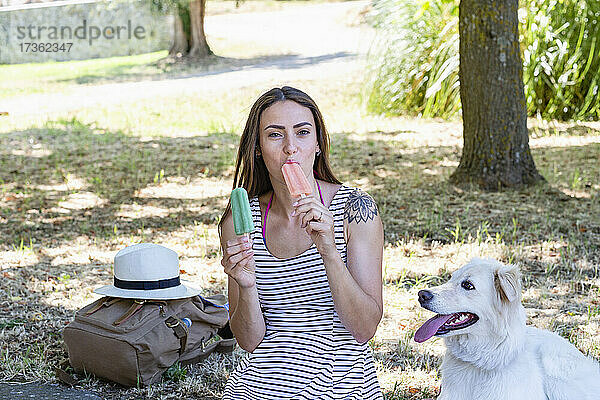Frau isst Eis  während sie bei einem Hund sitzt