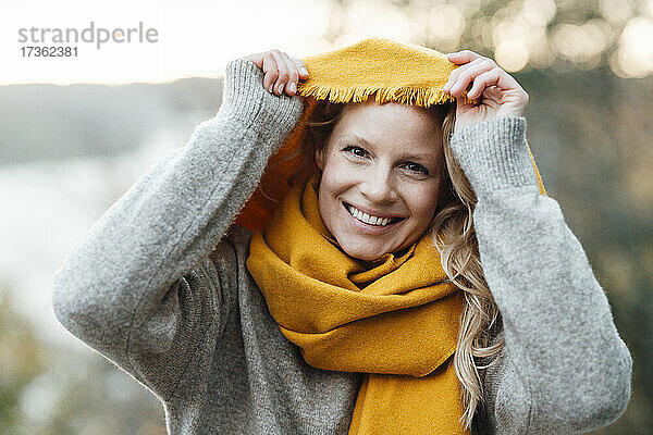 Frau lächelt und hält gelben Schal