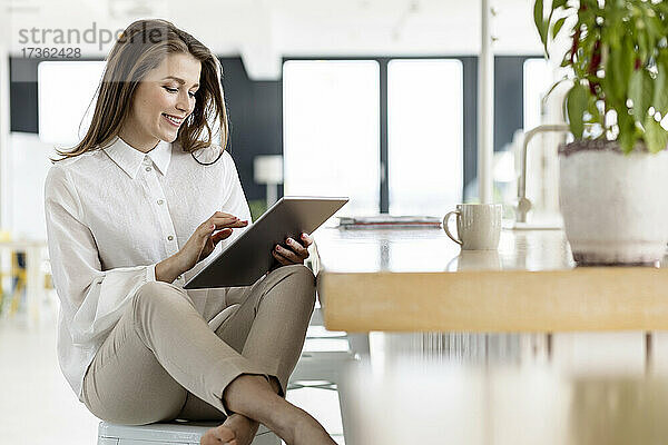 Geschäftsfrau  die ein digitales Tablet benutzt  während sie am Tisch im Büro sitzt