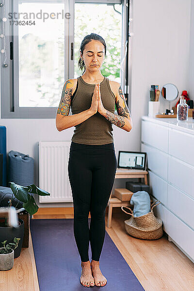 Mittlere erwachsene Frau meditiert und macht zu Hause Yoga