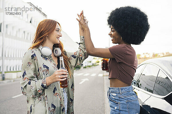 Lächelnde Freundinnen geben sich auf der Straße die Hand