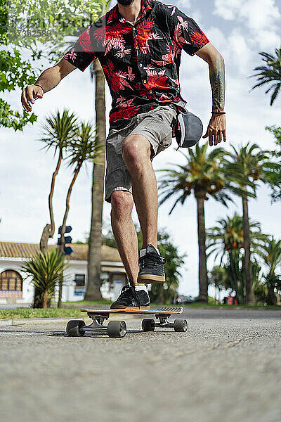 Mann balanciert beim Skateboardfahren auf der Straße