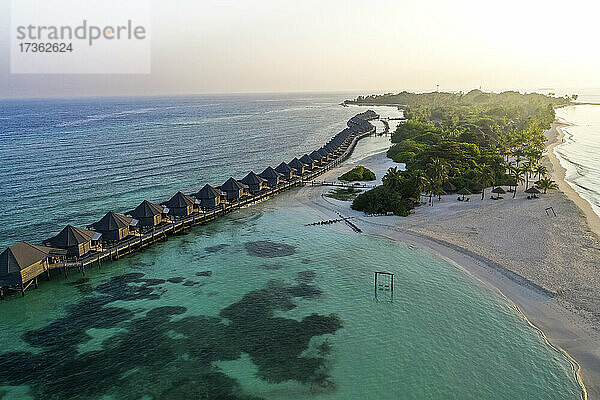 Malediven  Lhaviyani-Atoll  Kuredu  Luftaufnahme des Küstenstrands und einer Reihe von Resort-Bungalows bei Sonnenaufgang