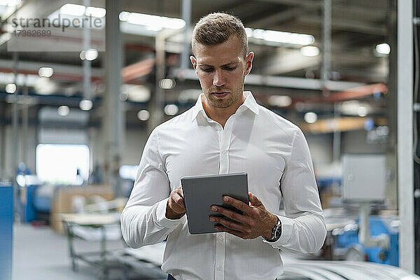 Junger Geschäftsmann benutzt digitales Tablet in der Industrie