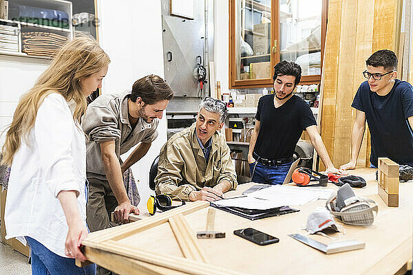 Ein Team von Schreinern diskutiert am Tisch in der Werkstatt