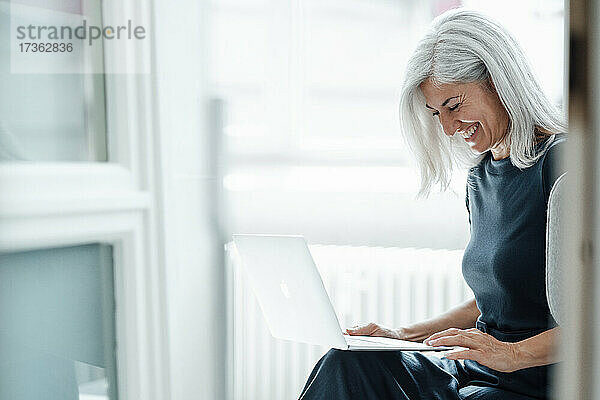 Glückliche Geschäftsfrau mit Videogespräch über Laptop im Büro
