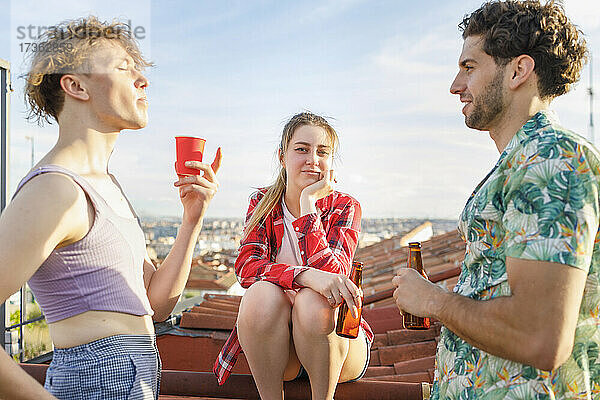 Junge Freunde unterhalten sich am Wochenende bei einem Drink auf einem Dach