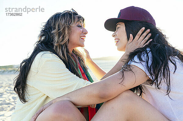 Lesbisches Paar schaut sich am Strand sitzend an